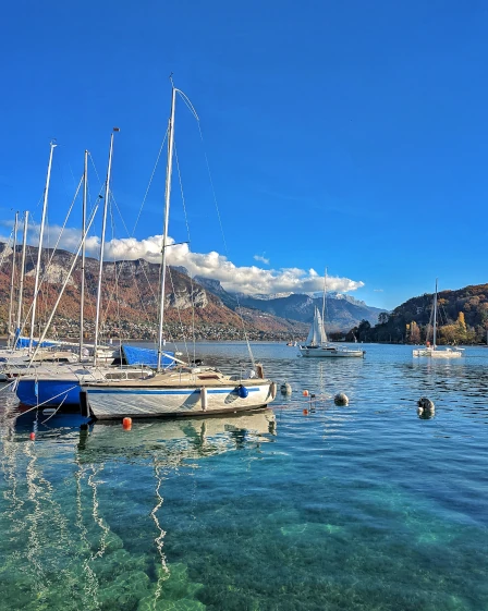 Beautiful clear water and sail boats docked on Lake Annecy in France on a sunny day
