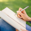 Image of a woman writing in a notebook in the park.